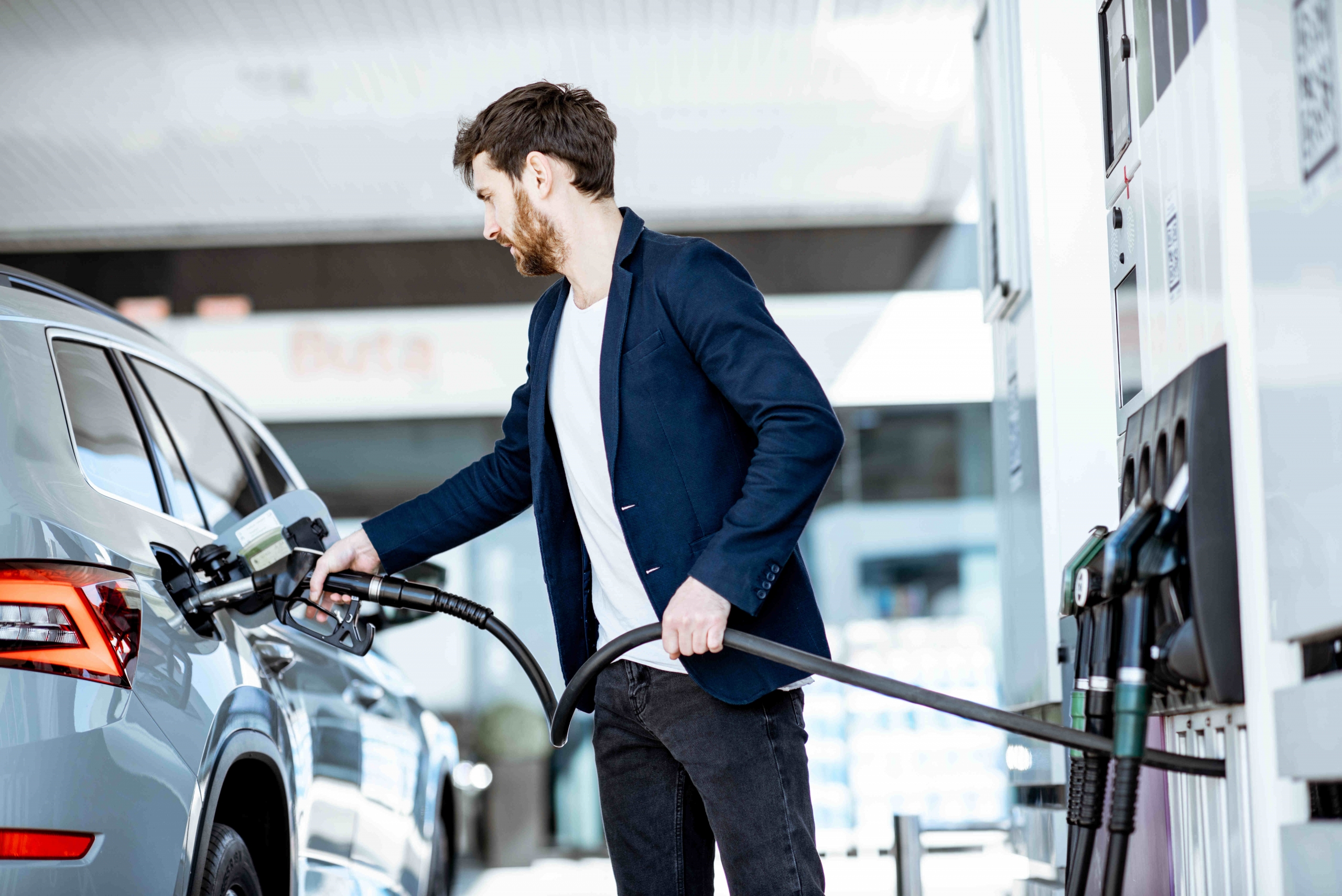 http://Businessman,refueling,his,luxury,car,holding,filling,gun,at,the